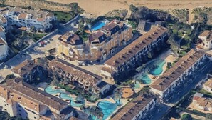 An aerial view of a coastal resort with multiple buildings, a large swimming pool, and a beach in the background. - Beachfront in Denia Alicante (Dénia)