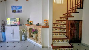 A living room with a fireplace, a television, and a staircase with patterned tiles. - Beachfront in Denia Alicante (Dénia)