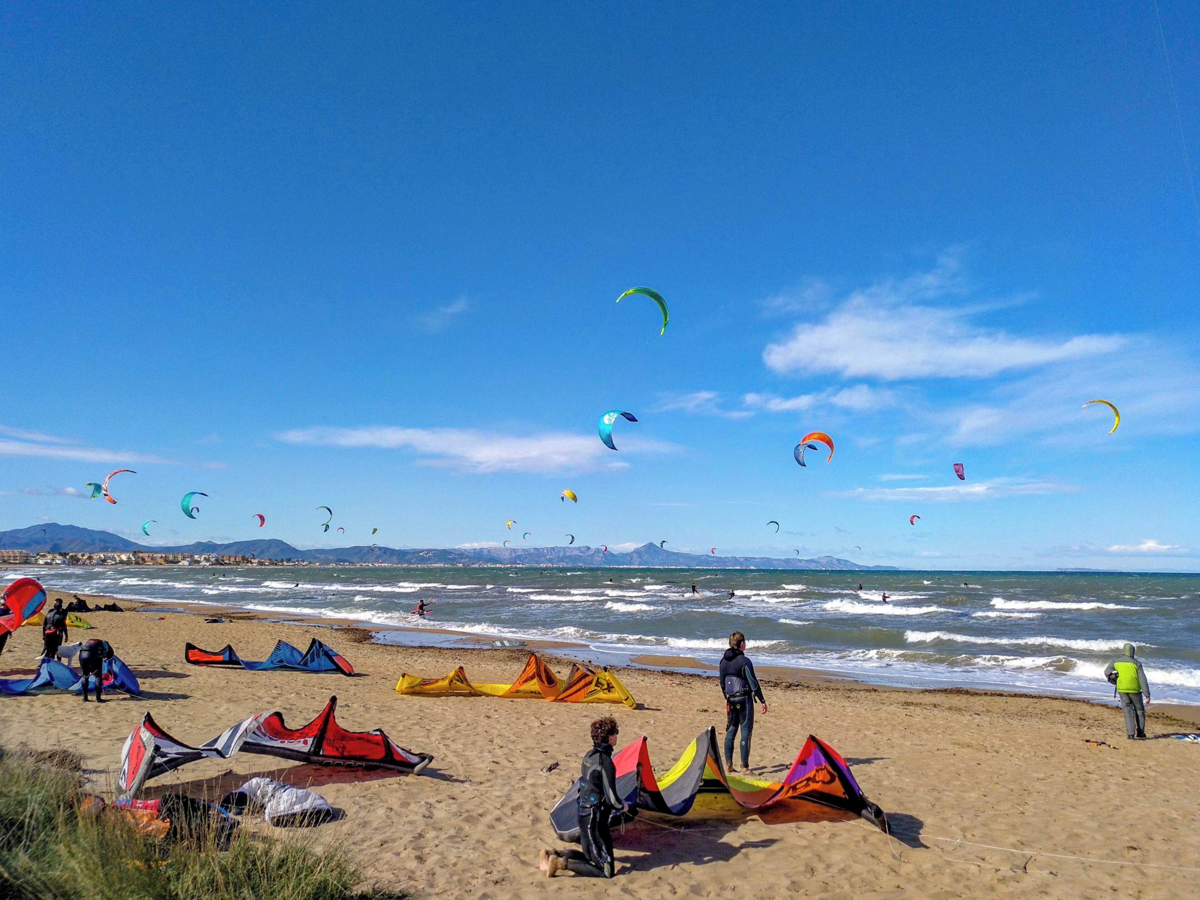 Ein Strand mit Menschen und bunten Drachen.