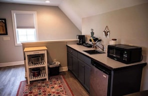 A compact kitchen with a microwave, coffee maker, and a small shelf unit.