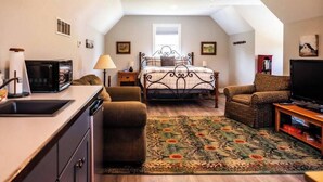 A bedroom with a bed, a television, a sofa, a small table, and a window.