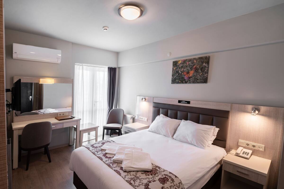 Une chambre d’hôtel avec un lit, un bureau, une chaise et un tableau au mur.