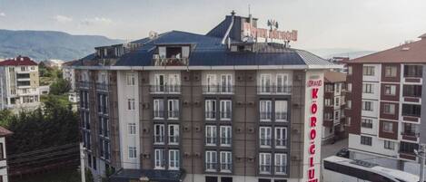 A multi-story hotel with balconies, a parking area, and a bus service nearby.