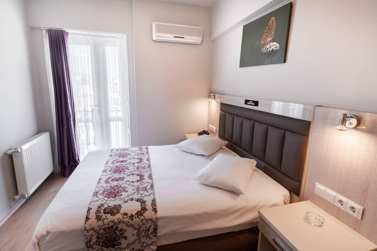 Une chambre d’hôtel équipée d’un lit, d’une table de chevet et d’un climatiseur fixé au mur.