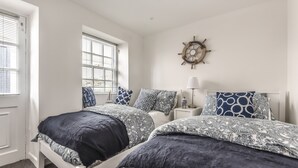A bedroom with two beds, a ship's wheel decoration, and a window with blinds. - Cottage - Sleeps 6 - Pet Friendly - Patio (St Austell)