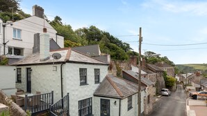 A narrow street lined with traditional stone houses, a small patio with outdoor seating, and a clear view of the street. - Cottage - Sleeps 6 - Pet Friendly - Patio (St Austell)