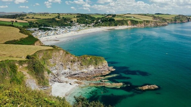 A coastal landscape with a beach, clear blue waters, and rolling hills in the background. - Cottage - Sleeps 6 - Pet Friendly - Patio (St Austell)