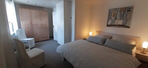 Une chambre à coucher avec un lit, des lampes de chevet, une chaise et une armoire.