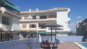 A rooftop terrace with a pool, outdoor seating, and a building with balconies. - Holidays in Tamarit beach  (Santa Pola)