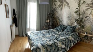 Une chambre avec un lit, un luminaire suspendu, une échelle et une fresque murale.
