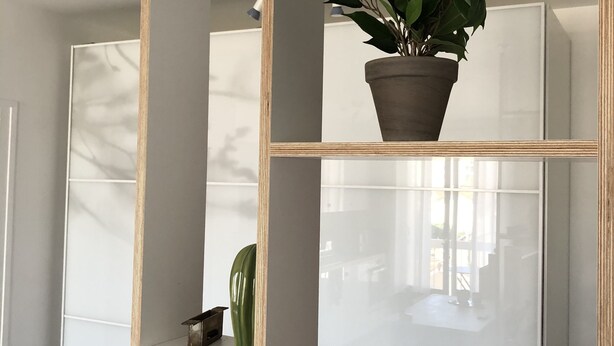 Une pièce avec une étagère en bois sur laquelle sont posés un pot de fleurs, un panier en osier et un petit objet décoratif.