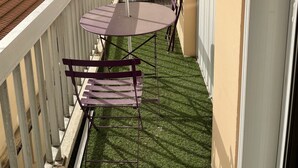 Un balcon avec une table et des chaises, un étendoir et une vue sur un bâtiment en arrière-plan.