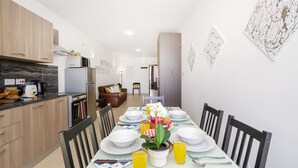 Eine moderne Küche mit Holzausstattung, ein Essbereich mit Tisch für vier Personen und eine Wohnbereich mit Sofa und Sesseln.