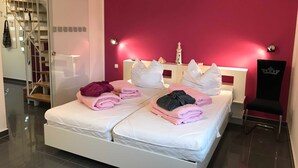 A modern hotel room with a large bed, a chair, and a staircase.