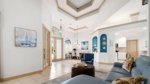 Amplia sala de estar con un sofá azul, una mesa de centro y un comedor con mesa y sillas.