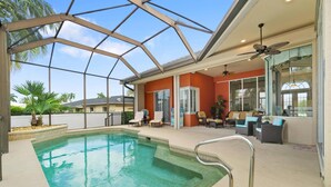 Un área de piscina exterior techada con techo de vidrio, sillas de descanso y una zona de estar con mesas.