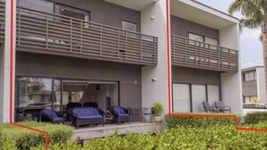 Un bâtiment moderne à deux étages, doté d’un balcon, d’un espace extérieur aménagé pour s’asseoir et d’un jardin bien entretenu.