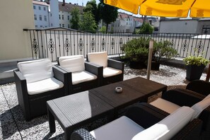 Un espace extérieur aménagé avec des meubles en osier et un parasol jaune.