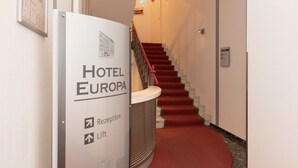 Una recepción de hotel con una escalera que sube a los pisos superiores.