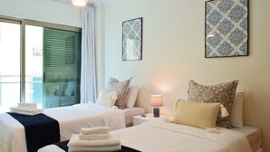 A hotel room with two beds, a nightstand with a lamp, and two patterned wall art pieces. - Machico Beach, a Home in Madeira (Machico)