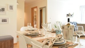 A dining area with a table set for four, including wine glasses, plates, and cutlery. There is a decorative vase and a metal bucket on the table. - Machico Beach, a Home in Madeira (Machico)
