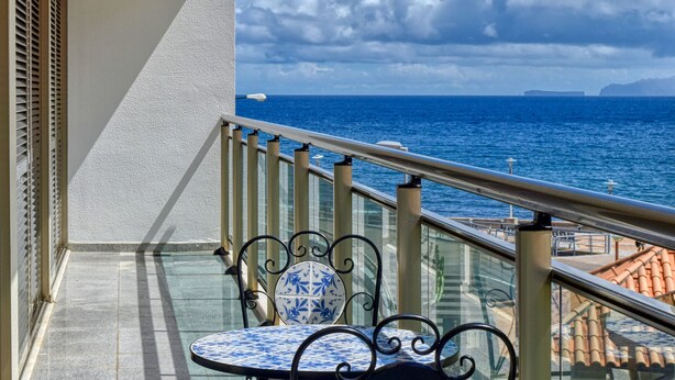 A balcony with a view of the sea, a patterned table, and a chair. - Machico Beach, a Home in Madeira (Machico)