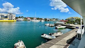 A marina with various boats docked, a building with a red roof, and a clear blue sky. - Studio in the heart of Saint François on the Marina (Saint francois)