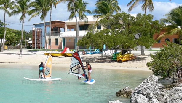 A beach with windsurfing equipment and palm trees. - Studio in the heart of Saint François on the Marina (Saint francois)