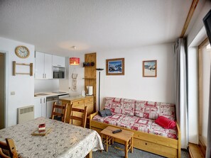 A compact living space with a kitchenette, a dining area, and a sofa.