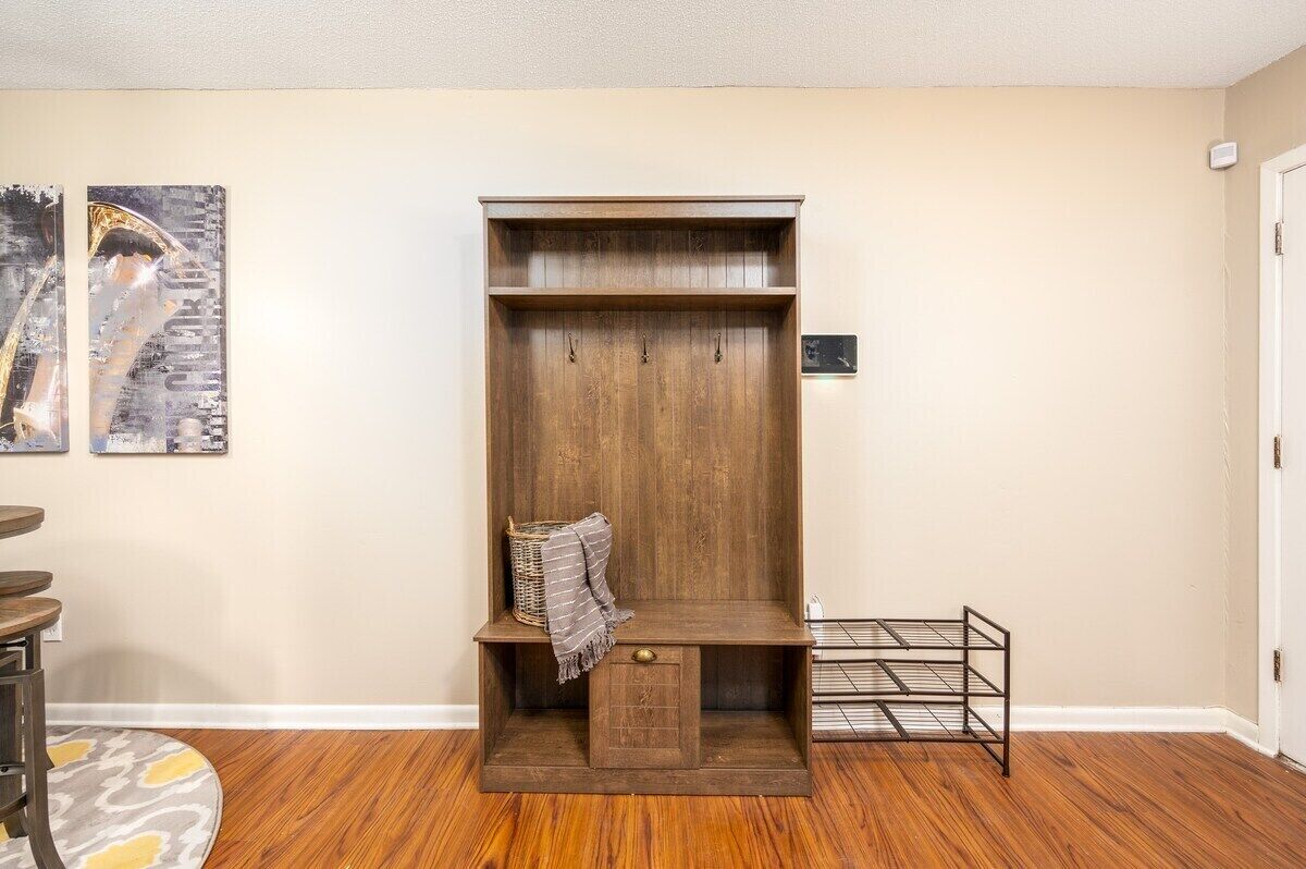 A room with a wooden bench, a metal shelf unit, and a small rug.