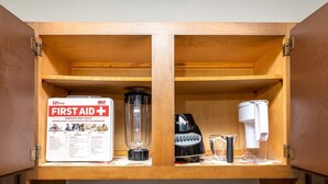 Un meuble en bois contenant une trousse de premiers secours, un mixeur et une machine à café.