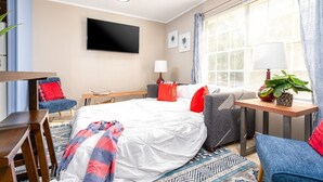 Quarto de hotel com cama, televisão, escrivaninha e cadeira.