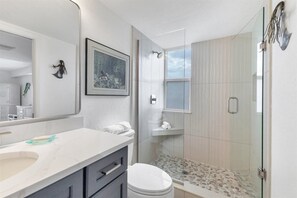 A modern bathroom with a large mirror, a framed artwork, a shower with a glass door, and a toilet. - Horizons West #701 - Incomparable View - Siesta Key / Crescent Beach (Sarasota)