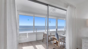 Une pièce dotée d’une grande porte-fenêtre coulissante donnant sur un balcon avec vue sur la plage.