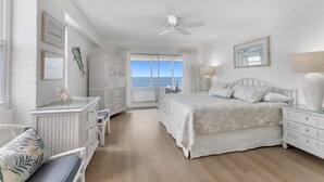 Une chambre à coucher avec un lit, un bureau, une chaise, une armoire et une vue sur l’océan.
