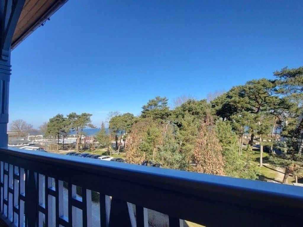 A balcony with a view of a residential area, including trees and houses.