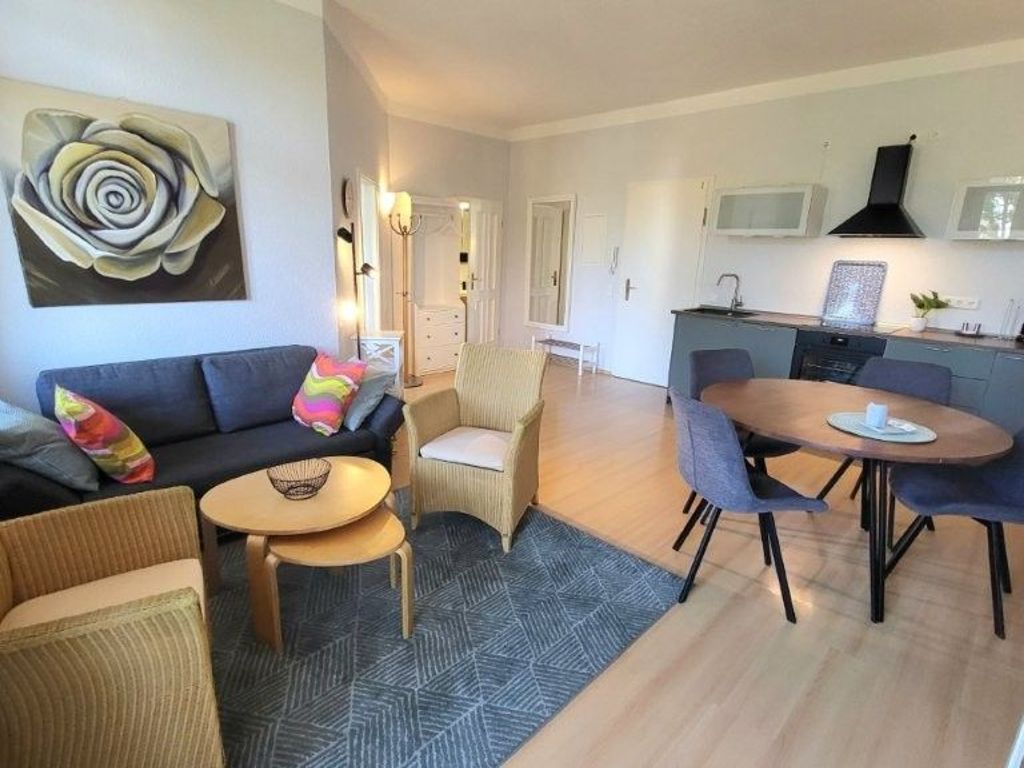 A modern living room with a sofa, armchairs, a coffee table, and a dining area with a table and chairs.