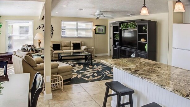A modern kitchen with a marble countertop, a dining area with a table and chairs, and a living room with a sofa and a coffee table. - Horizons West Villa A-11 - on Siesta Key's #1 Beach (Sarasota)