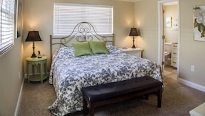 A bedroom with a bed, two bedside tables with lamps, a bench, a ceiling fan, and a door leading to a bathroom. - Horizons West Villa A-11 - on Siesta Key's #1 Beach (Sarasota)