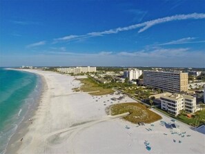 Un hôtel situé sur la côte, avec vue sur la plage, composé de plusieurs bâtiments et bénéficiant d’un ciel dégagé.