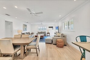 Un vaste salon comprenant une table à manger en bois, des canapés et un ventilateur de plafond.