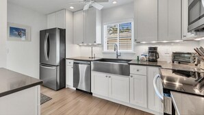 A modern kitchen with stainless steel appliances, white cabinetry, and a window with blinds. - Horizons West Villa B-5 - Great Unit on a Great Beach (Sarasota)
