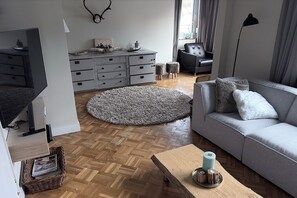 A modern living room with a grey sofa, a wooden coffee table, a grey rug, a grey dresser, and a black chair. - Villa Annabelle, a luxury vacation home in Winterberg (Winterberg)