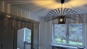 A bedroom with a bed, a chair, a radiator, and a window with a view of the outdoors.