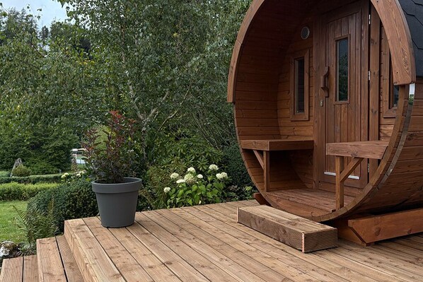 A wooden barrel-shaped structure with a door and windows, a potted plant, and a wooden deck. - Villa Annabelle, a luxury vacation home in Winterberg (Winterberg)