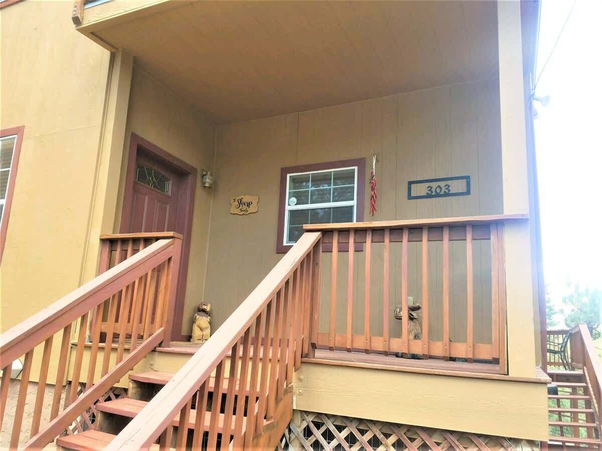 A building with a wooden staircase leading to a porch, a window with a number '303' sign, and a small statue on the wall.