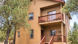 A two-story building with a balcony, a staircase, and a gravel driveway. - Mountain Hideaway (Ruidoso)