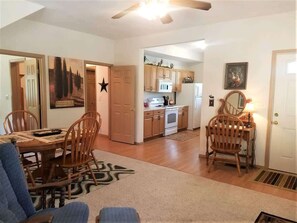 A spacious living room with a dining area, a kitchen, and a hallway.