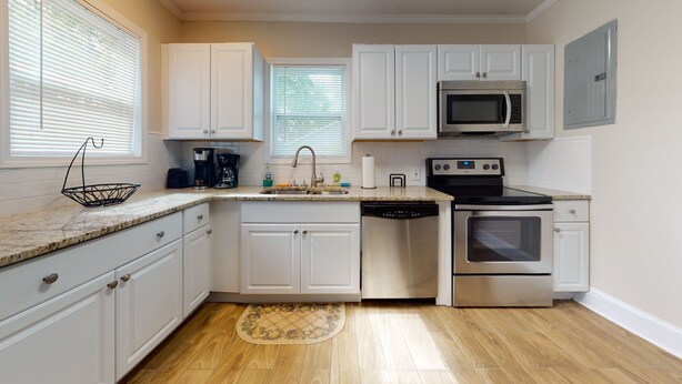 A kitchen with white cabinets, a stainless steel microwave, a dishwasher, and an oven. - Convenient to everything!! (Cartersville)