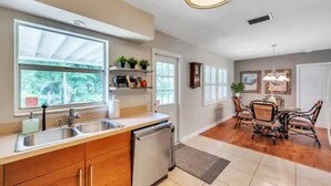 Una cocina moderna con lavavajillas, doble pileta y una zona de comedor con mesa y sillas.